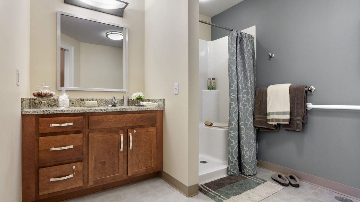A modern bathroom featuring a shower with a curtain, a vanity with a sink and mirror, and neatly arranged towels.