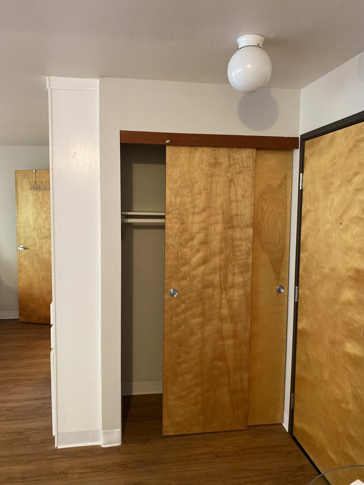 An empty room with a wooden sliding closet door and hardwood floor.