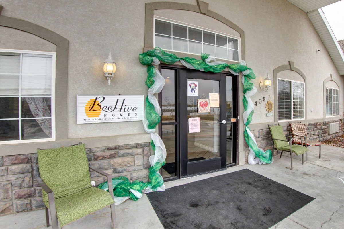 A decorated entrance with green and white adornments at a building with outdoor seating.