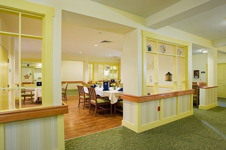 A cozy dining area with neatly arranged tables and chairs, bathed in warm light.