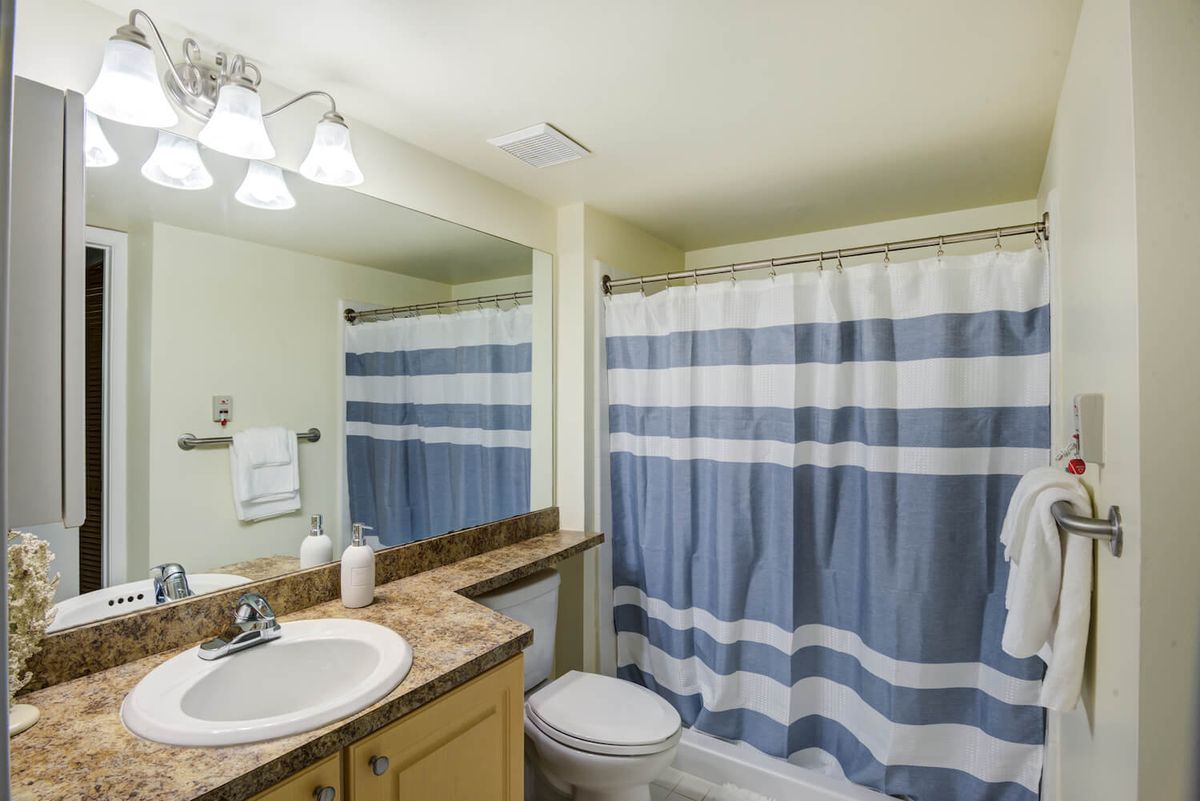 A clean and bright bathroom with a blue and white striped shower curtain.