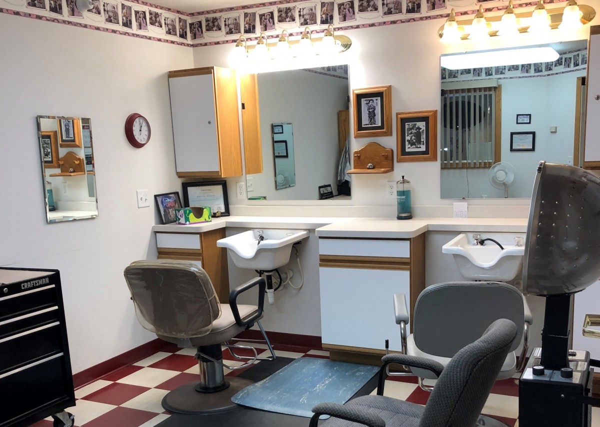 A small barbershop with classic style chairs, mirrors, and bright lighting.