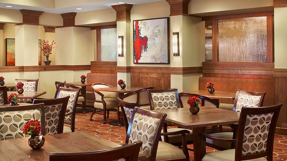 A cozy restaurant dining area with wooden furnishings and modern artwork on the wall.