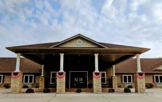 A symmetrical building entrance with columns under a partly cloudy sky.