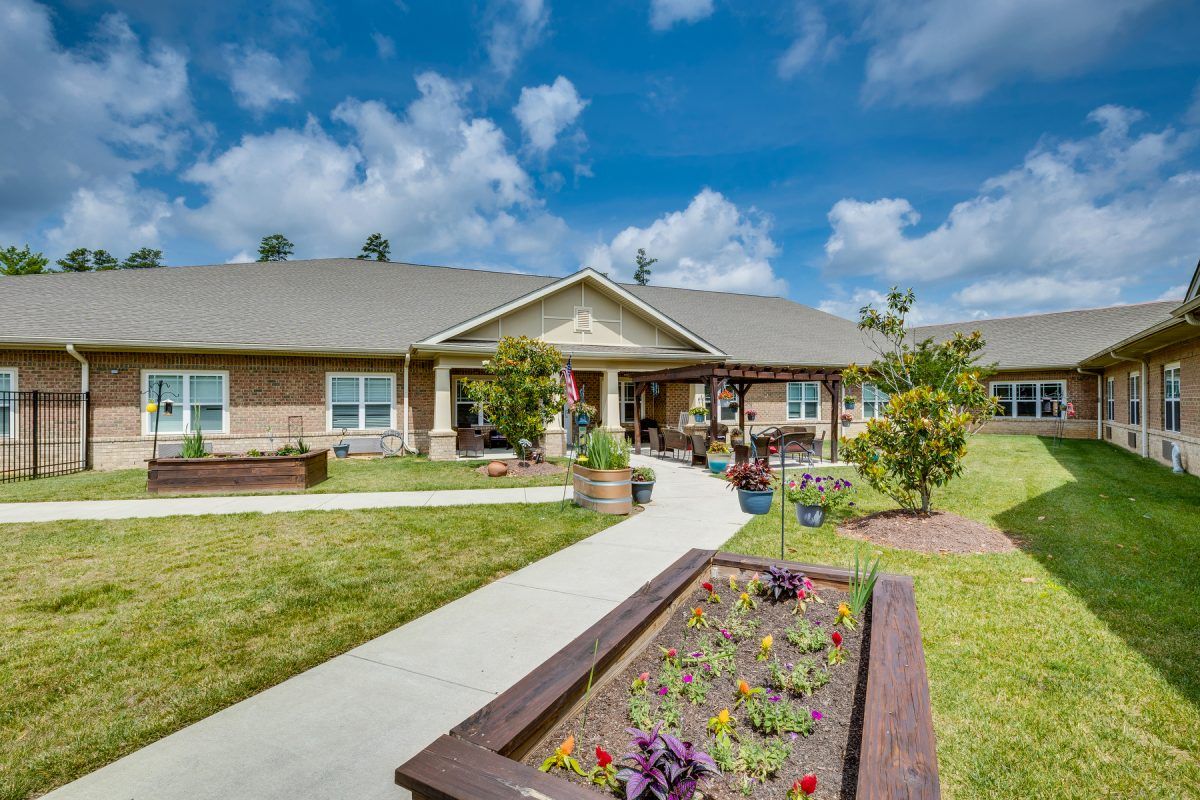 A well-maintained residential building with a garden under a partly cloudy sky.