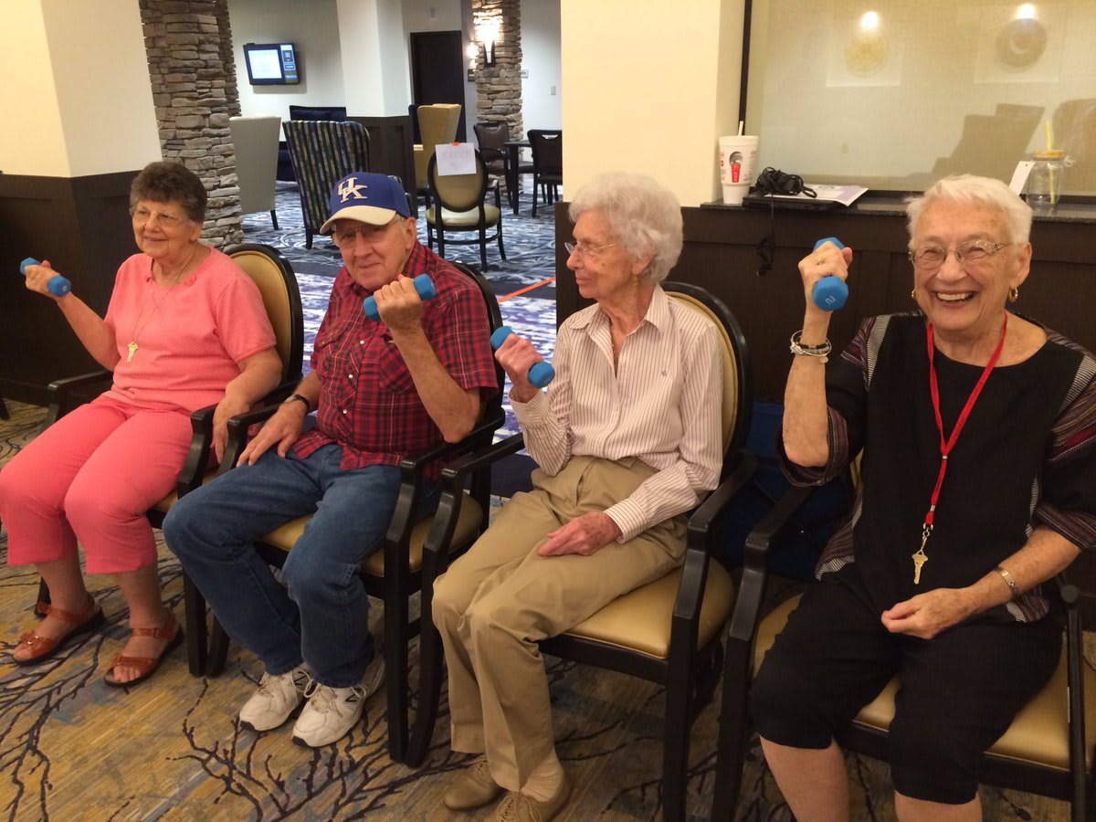 A group of seniors participating in a seated exercise session indoors.