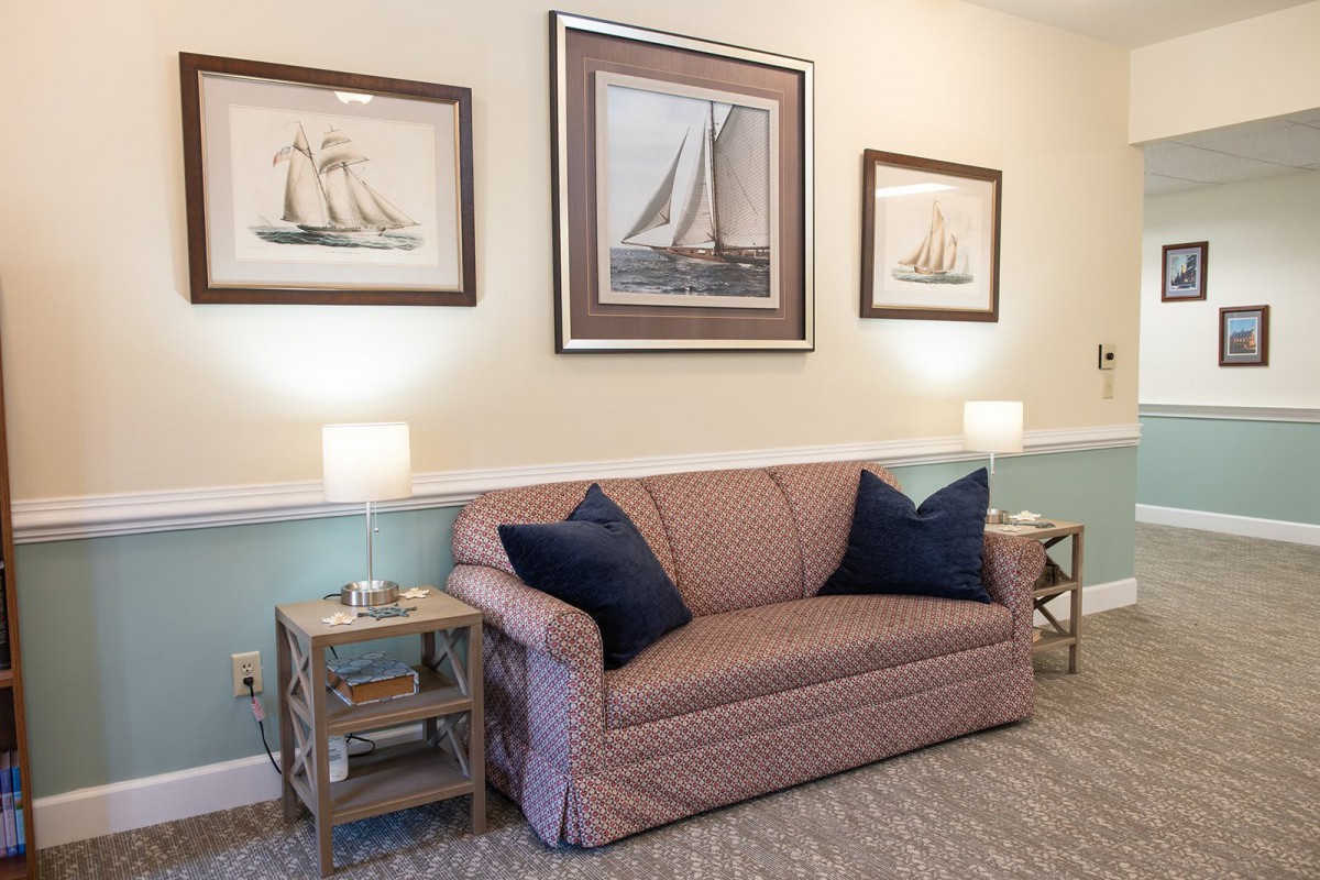A cozy living room with nautical-themed wall art, a comfortable sofa, and matching table lamps on either side.