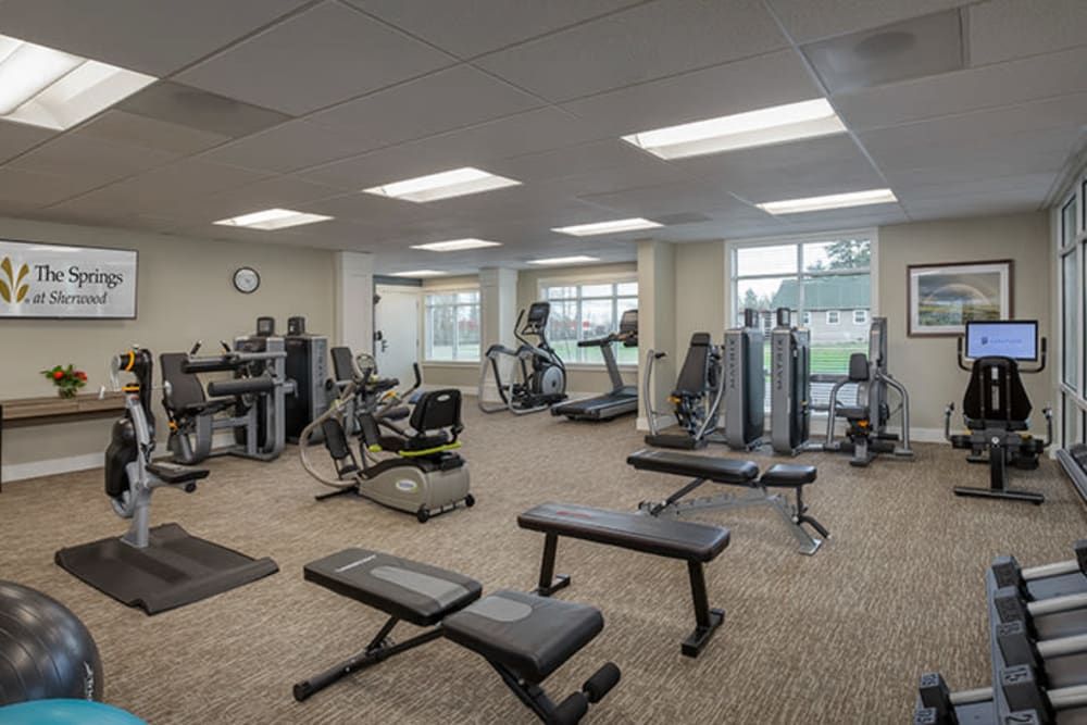 A modern gym equipped with various exercise machines and benches.