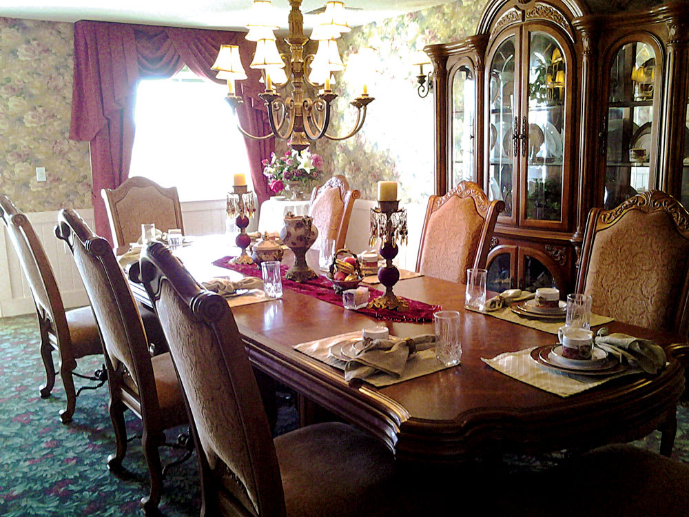 A traditional dining room with an elegant table setting, chandelier, and ornate furniture.