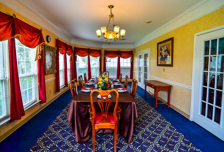 A well-decorated dining room with a large table, elegant chairs, and warm lighting.
