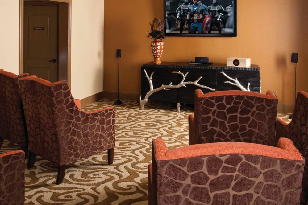 A stylish living room with animal print chairs and a home theater setup.
