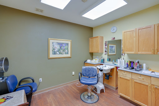 An interior view of a barber shop with a styling chair, mirror, and various hair products.