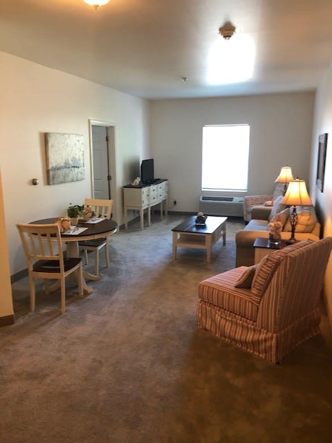 A cozy living room with furniture including a sofa, chairs, tables, and lamps.