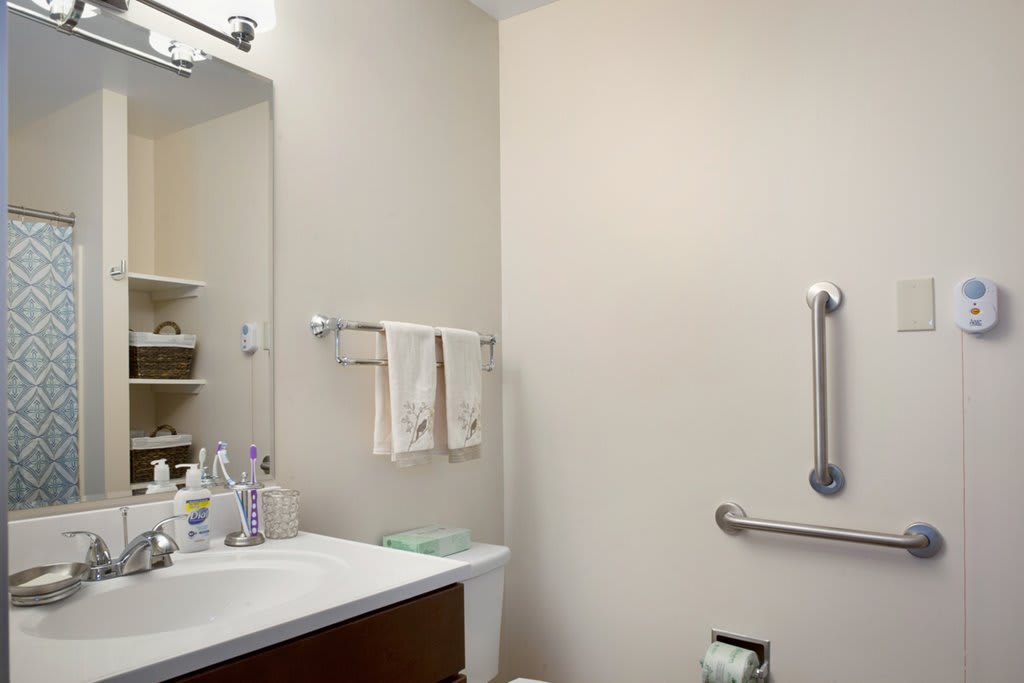 A clean bathroom with a sink, mirror, and towels neatly arranged on a rack.