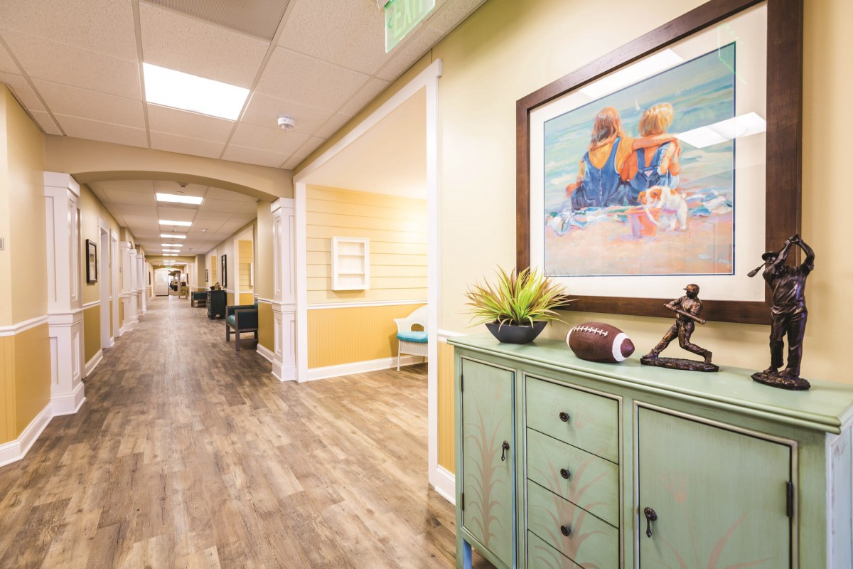 A well-decorated hallway with a wooden floor, featuring furniture and artwork.