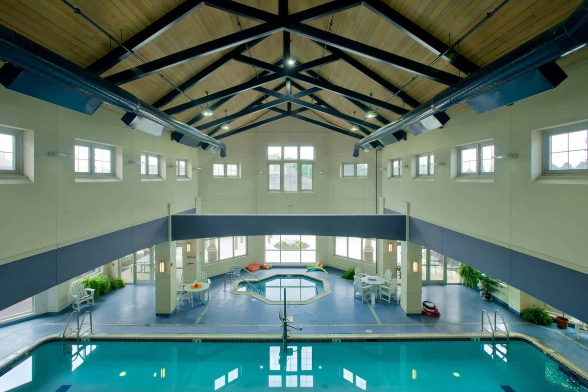 A spacious indoor pool area with high ceilings and ample natural light filtering through large windows.