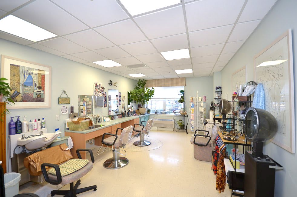 A spacious beauty salon interior with multiple stations, chairs, and various hair and beauty products displayed.