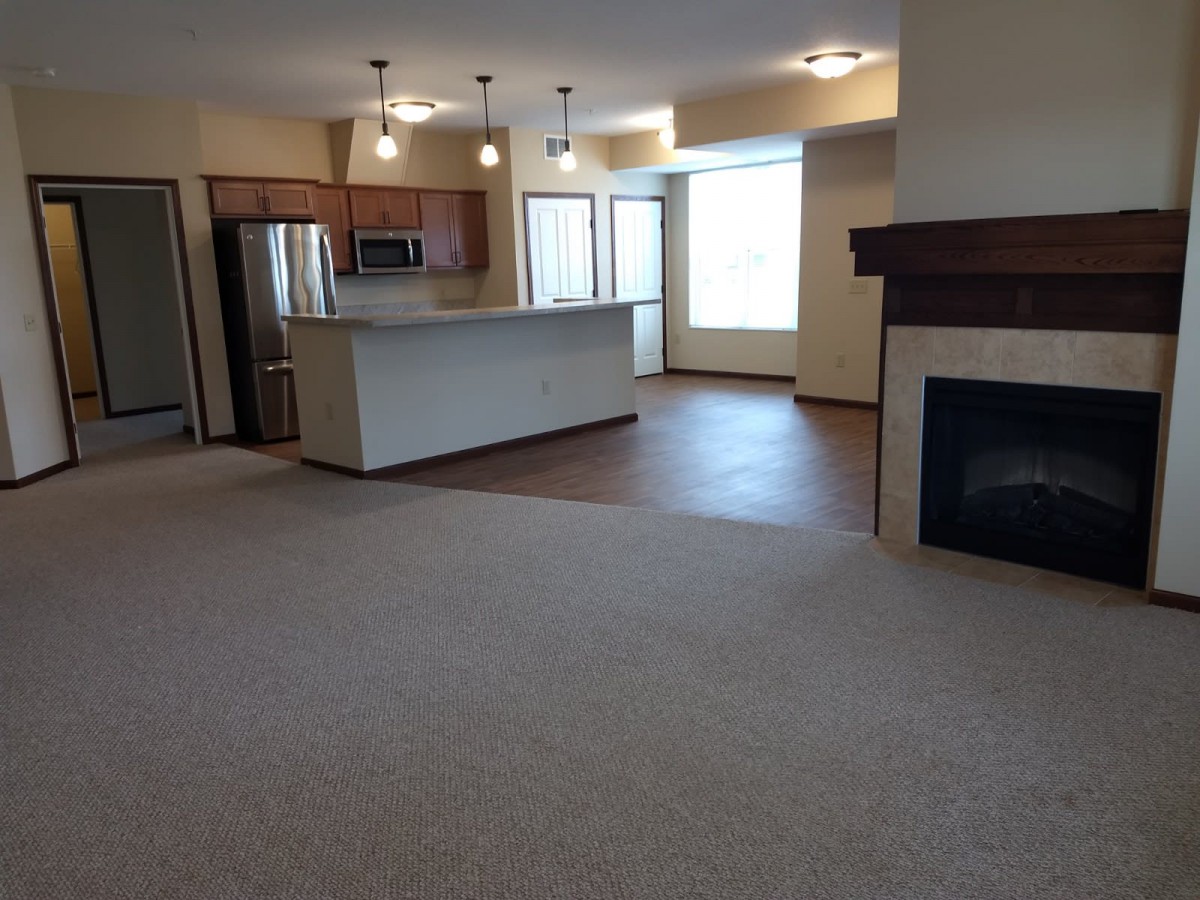 An open floor plan featuring a kitchen with an island and a living room area complete with a fireplace.