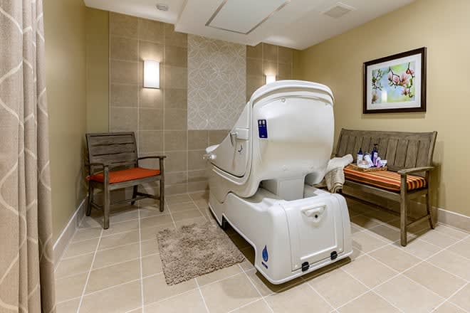 A luxurious spa room featuring a modern massage chair, comfortable seating, and relaxing decor.