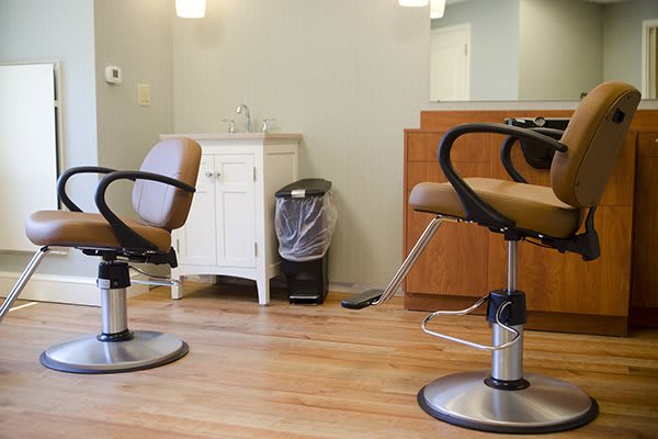 An empty hair salon with barber chairs and a mirror.