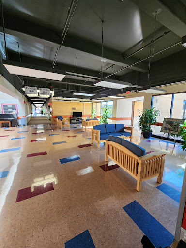 A spacious lobby featuring comfortable seating and greenery, designed for relaxation and interaction.
