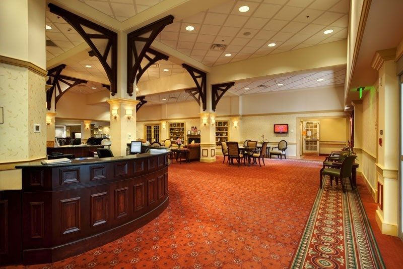 A well-lit hotel lobby with a reception desk and seating area.