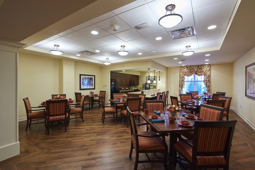 A warmly lit dining area with neatly arranged tables and chairs.