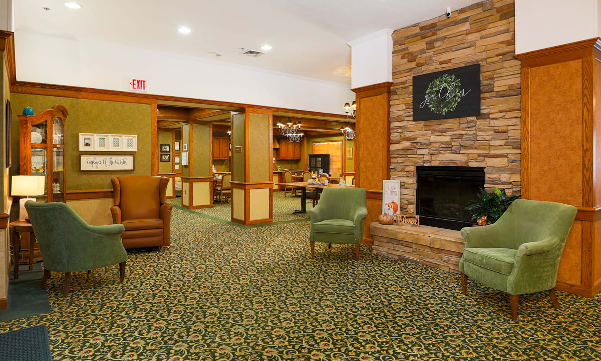 A cozy lobby area featuring a fireplace, comfortable armchairs, and warm lighting.