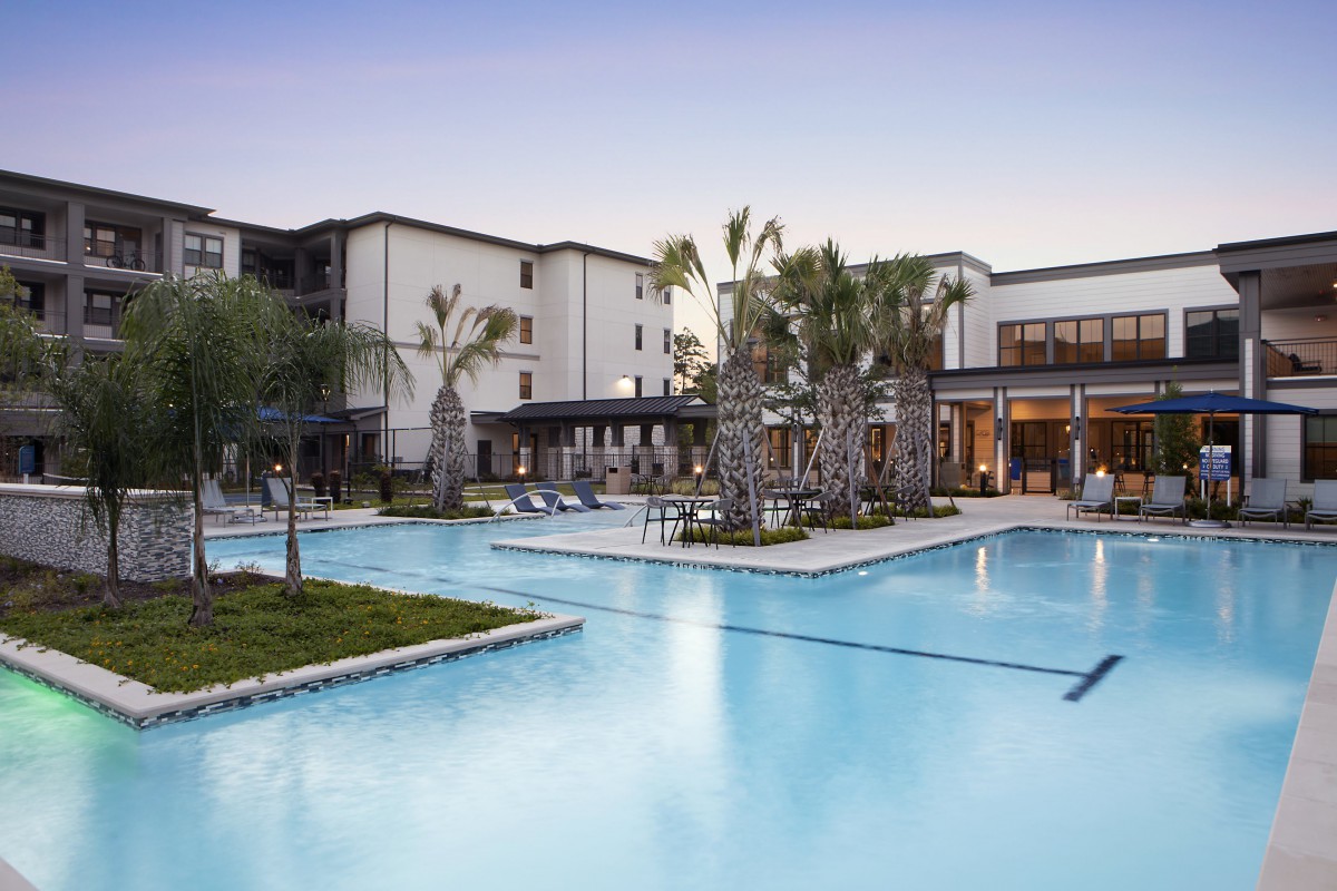 A luxurious hotel resort featuring a large outdoor swimming pool surrounded by palm trees.