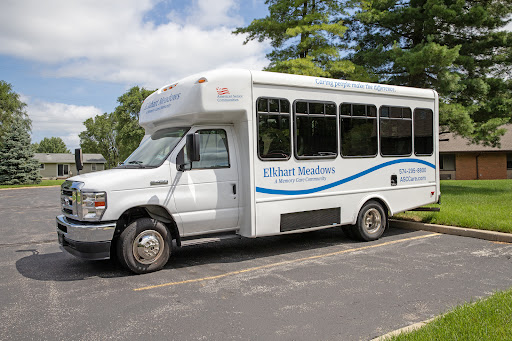 A white shuttle bus parked on the side of a road surrounded by greenery.