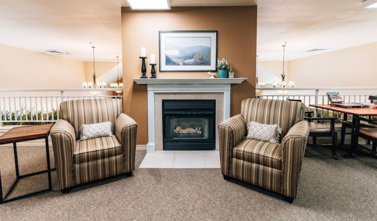 A cozy living room with striped armchairs flanking a fireplace.