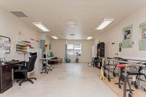 A tidy office space with desks and chairs, well-lit by overhead lights and a window.