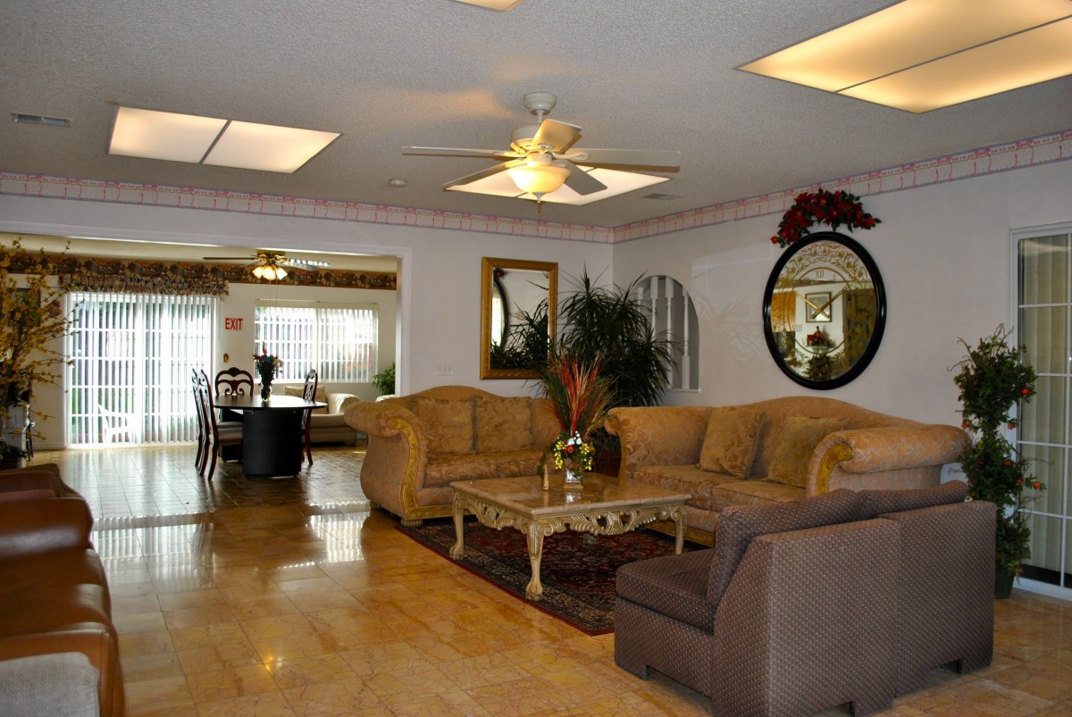 A spacious and elegantly furnished living room featuring a large sofa, a coffee table, and decorative elements such as mirrors and plants.