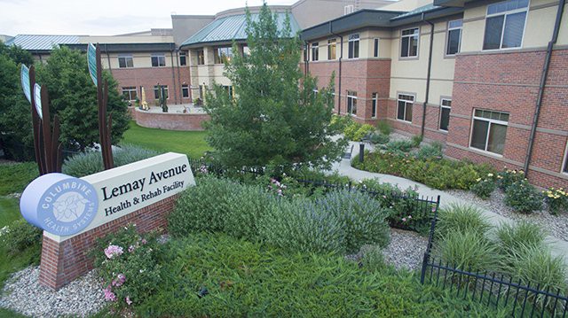 A well-maintained garden in front of a modern building with a pathway and prominent signage.