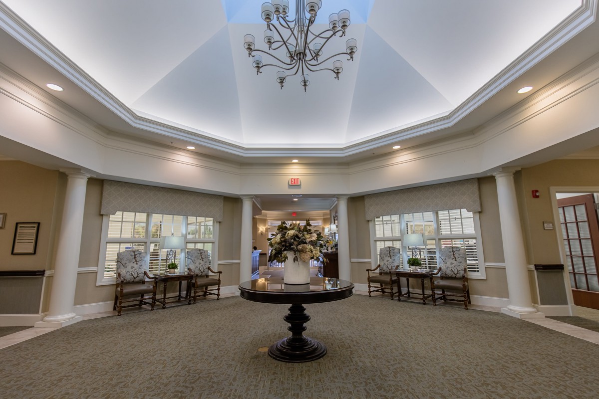 A spacious lobby with a central chandelier and decorative table, creating an inviting ambiance.