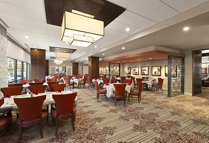 A spacious and elegantly decorated restaurant dining room with neatly arranged tables and chairs.