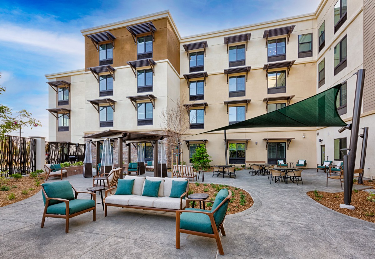 A modern hotel building with an inviting outdoor seating area in the courtyard.