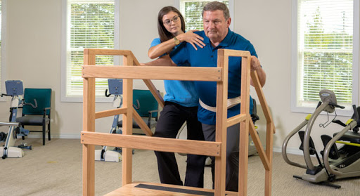 A physical therapist assisting an elderly man during rehabilitation exercises.