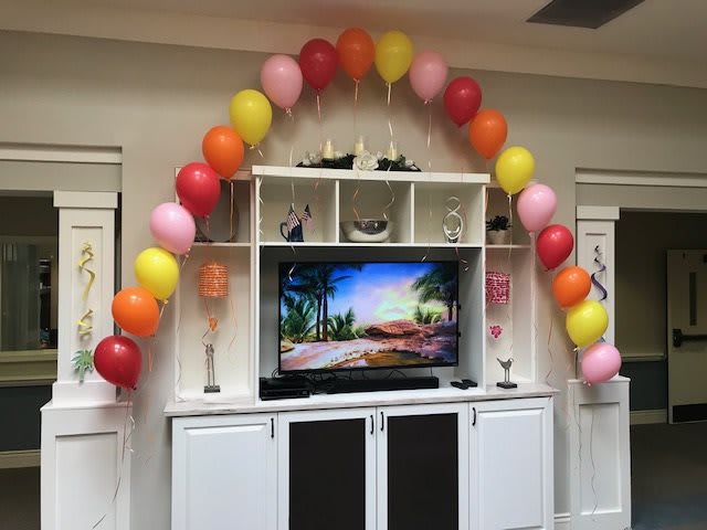 A living room decorated with colorful balloons arching over a TV stand, creating a festive atmosphere.