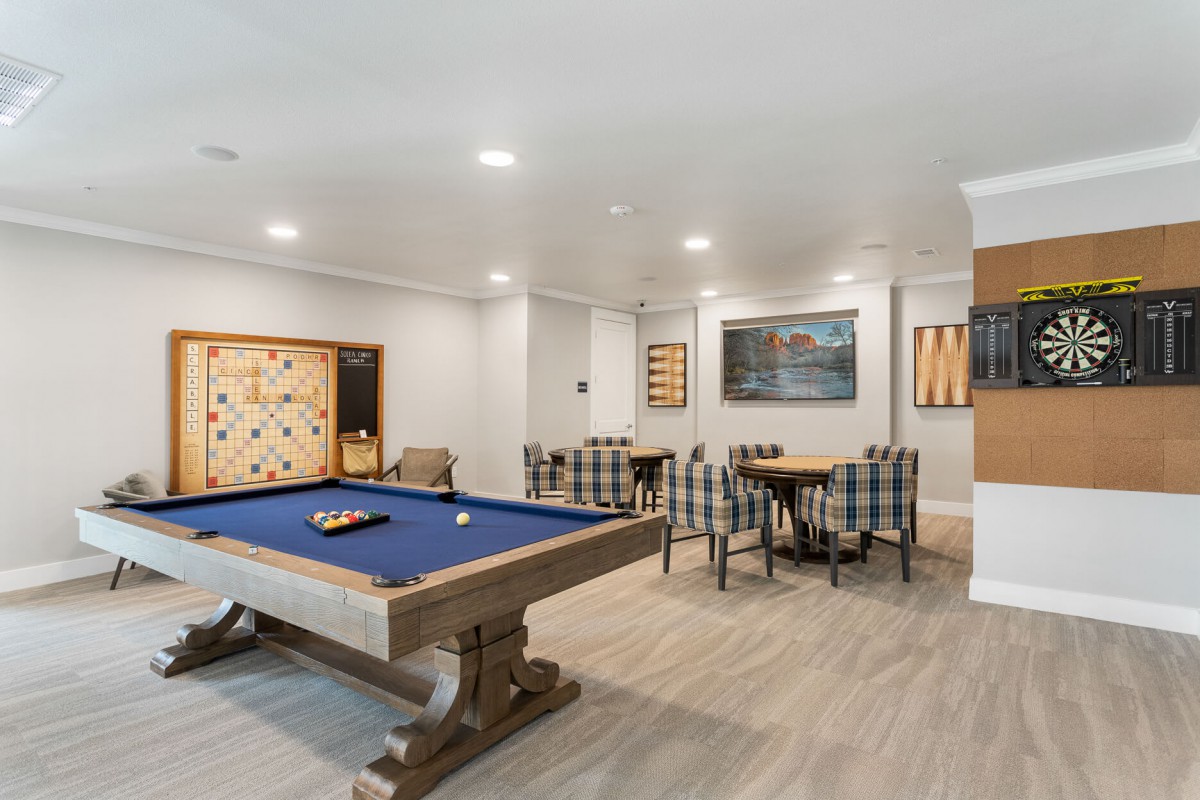 A modern game room featuring a pool table, scrabble board, and dining area.