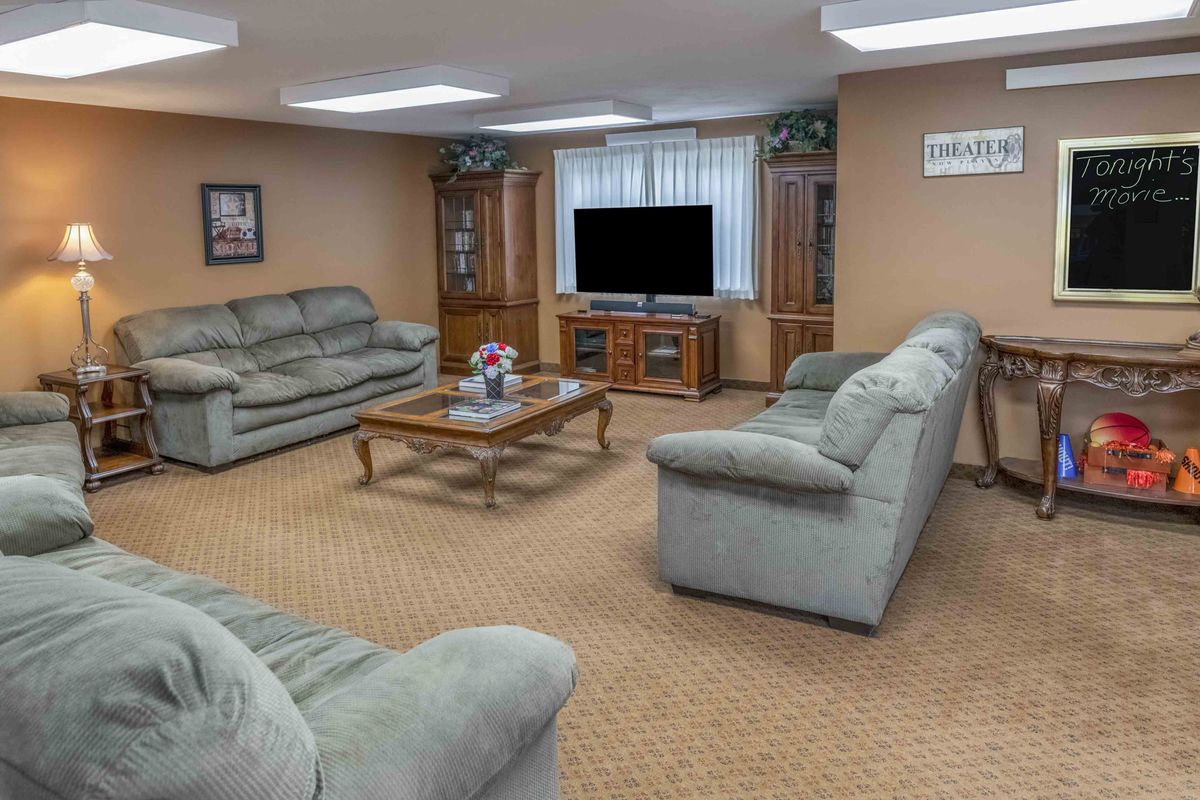 A cozy living room with plush sofas, a large television, and a coffee table on a carpeted floor.