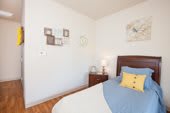 A cozy bedroom with a neatly made bed, bedside table, and wall decorations.