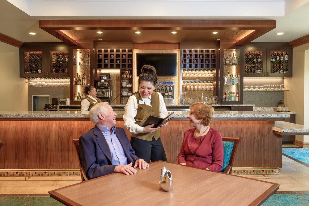 A waitress taking an order from a couple seated at a restaurant table.