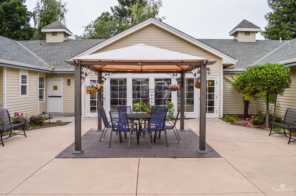 A cozy patio setup with a gazebo, complete with outdoor seating and hanging plants.