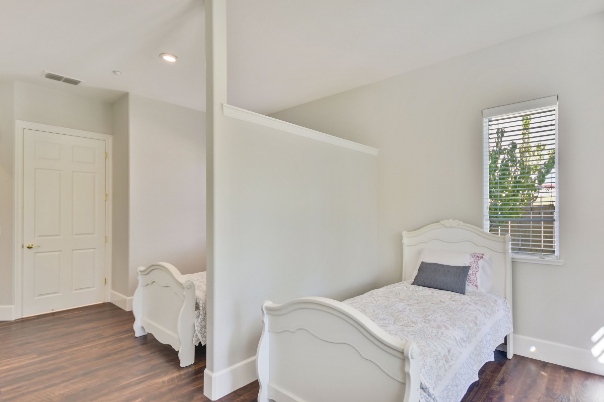 Minimalist bedroom with twin beds separated by a partition wall.