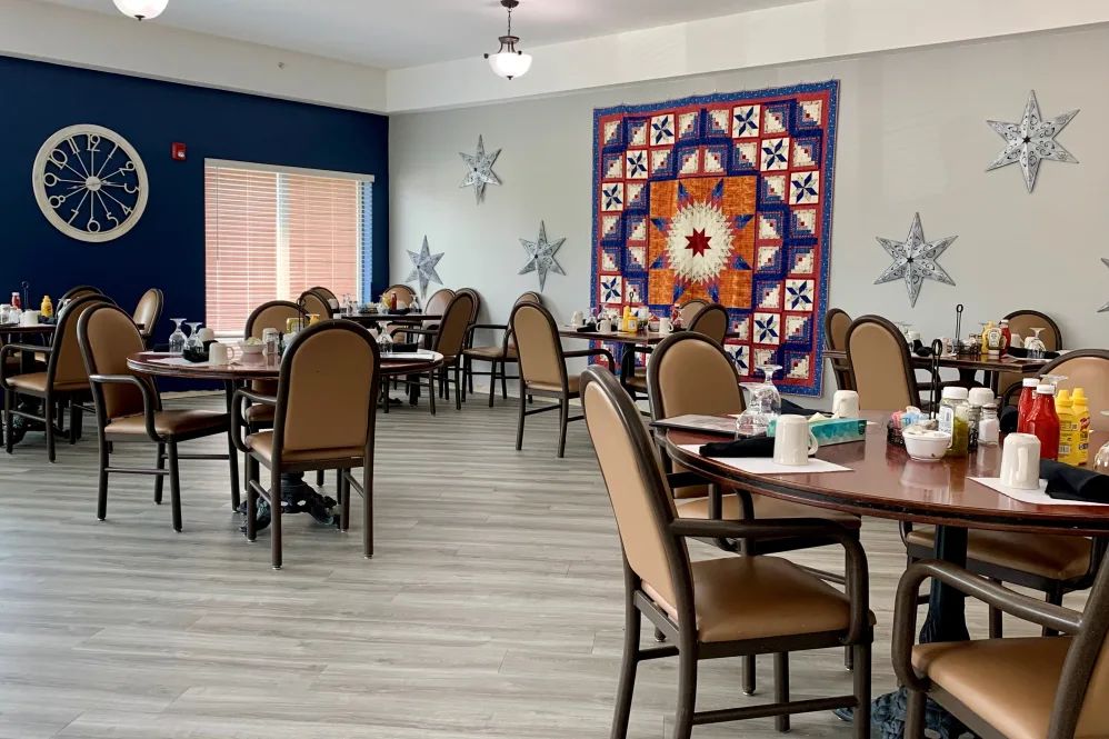 An empty dining room with decorated walls and neatly arranged tables and chairs.
