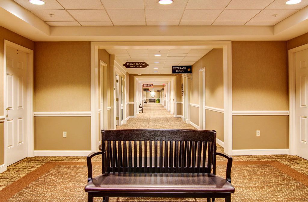 A symmetrical hallway with a wooden bench and multiple doors on either side.