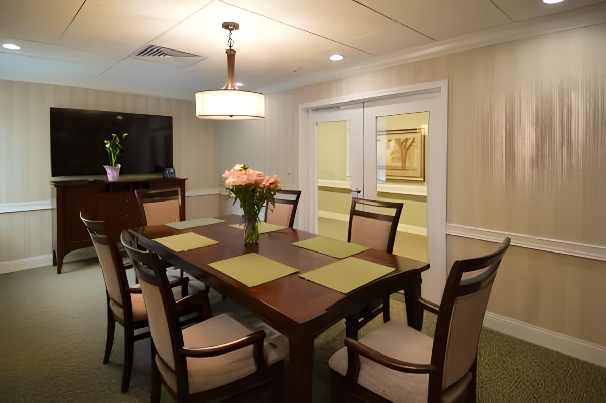 A well-decorated dining room with a wooden table and chairs, adorned with placemats and a bouquet of flowers under soft lighting.