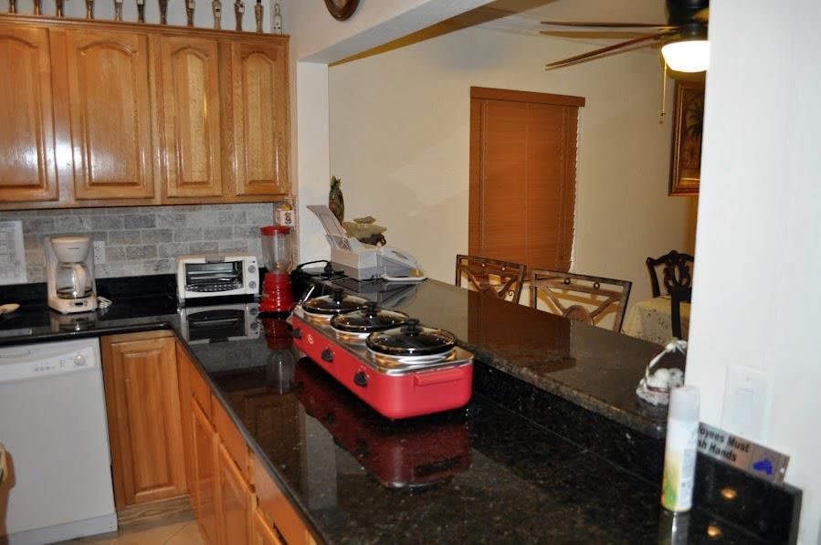 A kitchen with wooden cabinets, a red countertop stove, and a connected dining area.