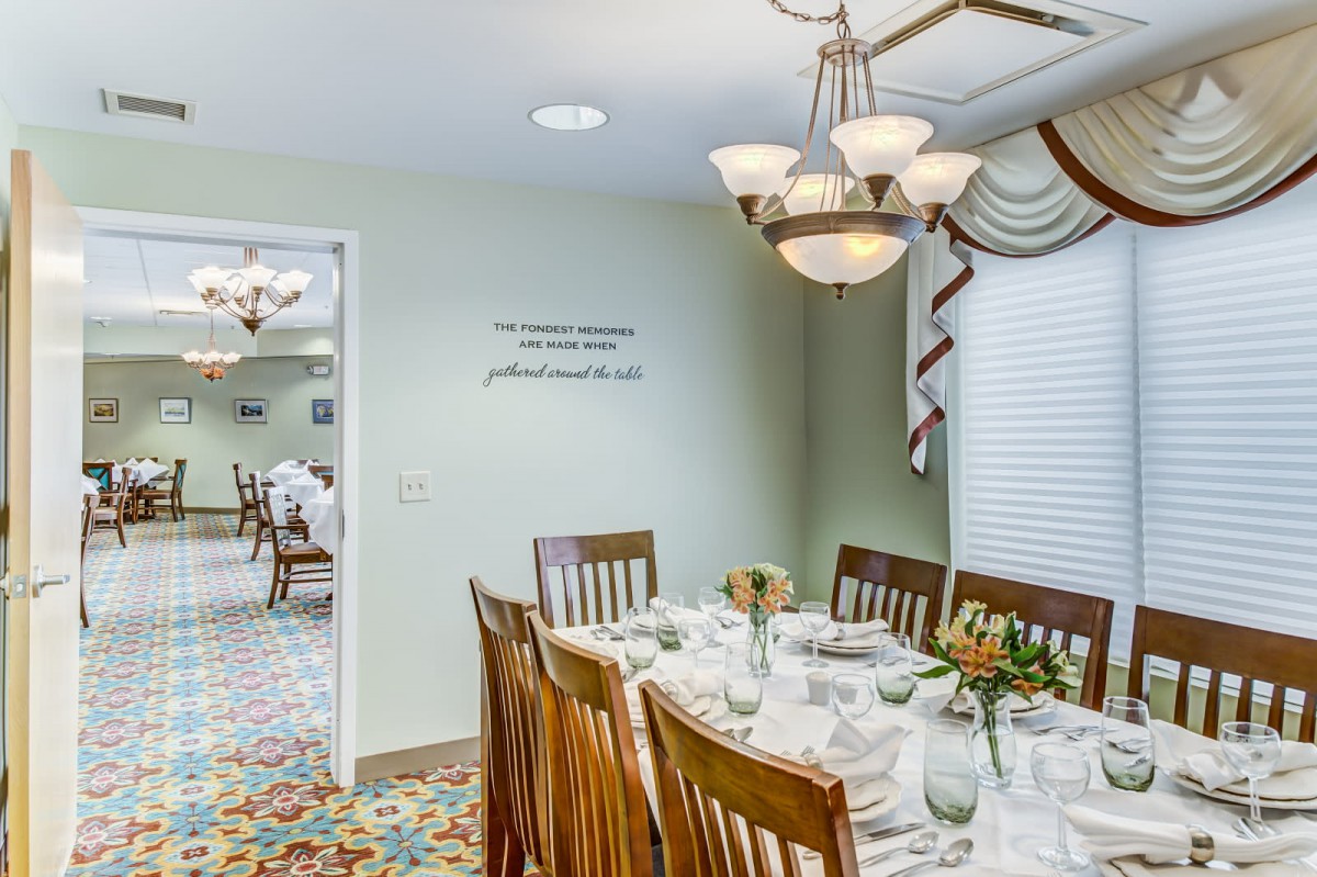 Elegantly set dining room with a chandelier and wooden chairs.